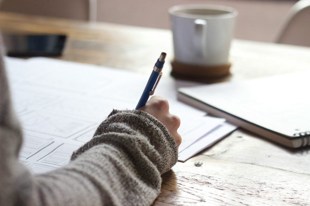 Person writing in a notebook studying,